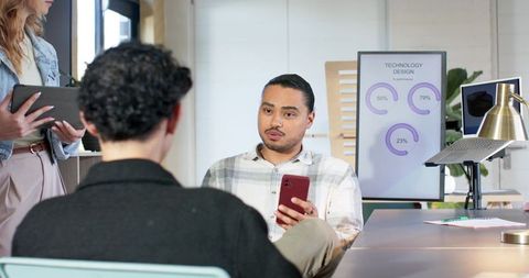 Diverse team reviewing technology charts and mobile data during office collaboration