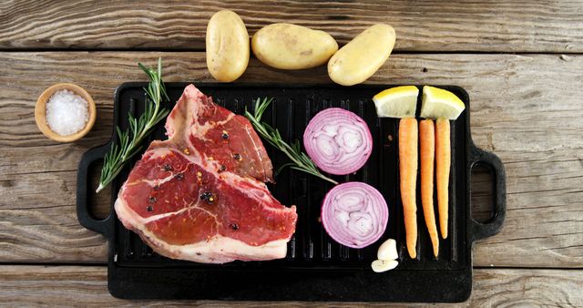 Raw steak seasoned with spices is ready for grilling, surrounded by fresh vegetables and herbs on a wooden surface, with copy space. A delicious meal preparation scene showcases the ingredients for a savory dish.