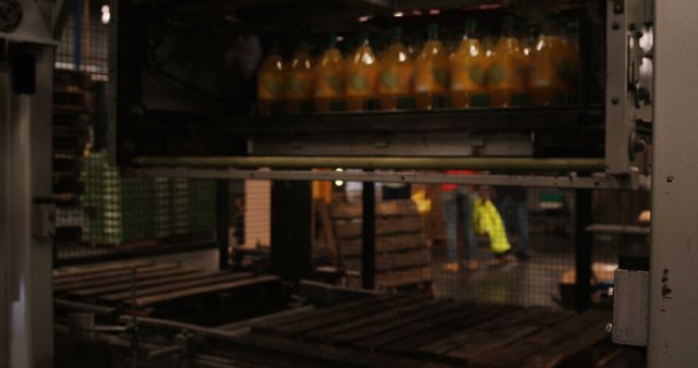 Image depicts a factory conveyor system moving orange juice bottles through a production line in an industrial setting. Suitable for use in materials related to manufacturing processes, automated industrial systems, beverage production, and factory operations.