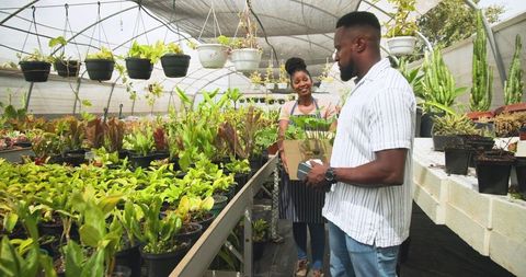 African american customer shops in greenhouse with smiling staff