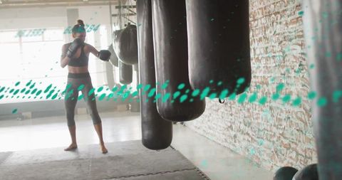 Female Boxer Training in Industrial Gym with Punching Bags