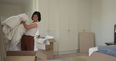 Young Woman Packing in Minimalist Bedroom Setting