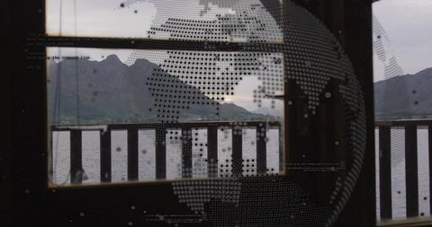 Framing centered mountain peaks through window with dotted global data overlay