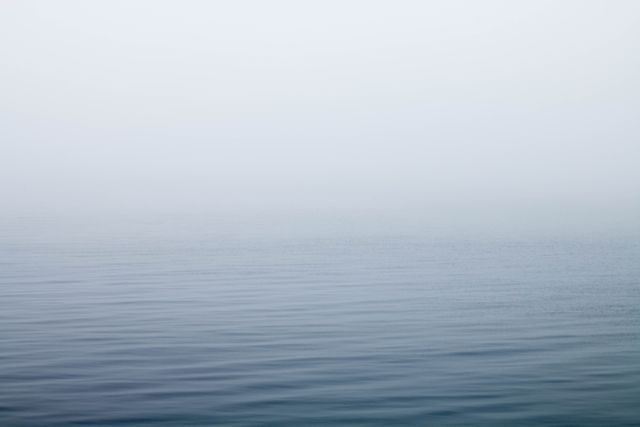 Calm waves meeting foggy sky in serene minimalist seascape. Ideal for backgrounds, meditation apps, relaxation materials, minimalist art projects, and nature conservation campaigns.