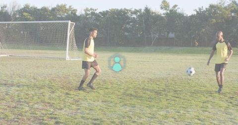 Two Male Soccer Players Practicing Passing Drills on Grass Pitch Near Goal in Morning Light