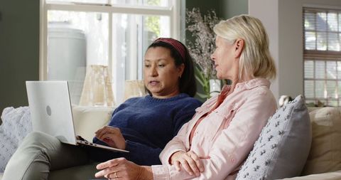Diverse Female Friends Browsing Laptop on Cozy Sofa