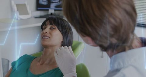 Dentist examining female patient jaw and teeth while viewing x-ray on monitor in clinic