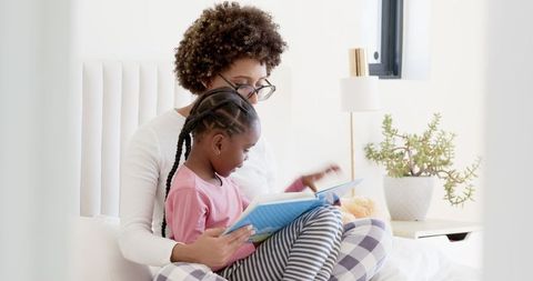 Mother and Daughter Reading Book in Peaceful Bedroom Setting