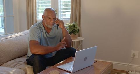 Senior Man Concentrated while Using Laptop at Home Office
