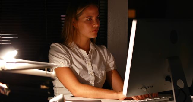 Dedicated woman working late at the office, focused on computer screen - Download Free Stock Photos Pikwizard.com