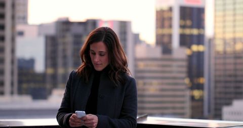 Businesswoman Using Smartphone with Urban Skyline