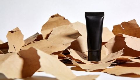 Standing matte black cosmetic tube on torn kraft paper showcasing minimalist packaging