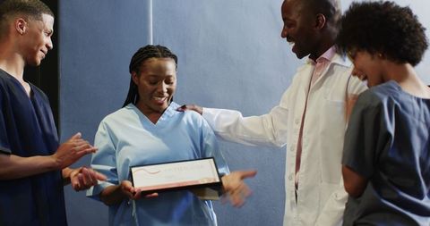 Medical team celebrating nurse achievement with award presentation