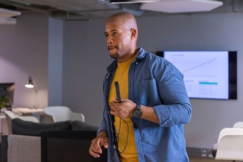 African american presenter holding wired microphone presenting analytics in modern office