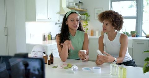 African american beauty influencers filming skincare tutorial at sunlit kitchen island