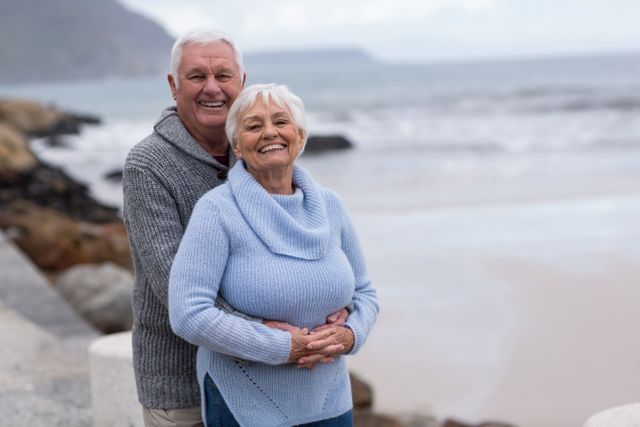 Senior Couple Embracing on Beach with Smiles - Download Free Stock Photos Pikwizard.com