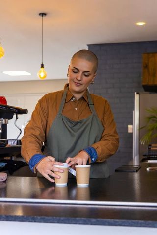 Barista preparing takeaway coffee cups at counter in warm industrial cafe ambience