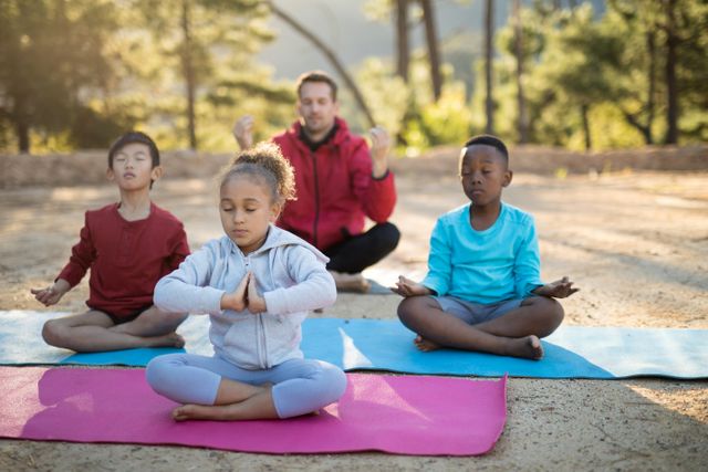 Coach guiding kids in meditation outdoors on a sunny day. Children sitting on yoga mats in a serene park setting, practicing mindfulness and relaxation. Ideal for use in articles or advertisements about children's wellness, outdoor activities, mental health, and fitness programs.