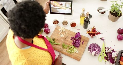 Woman cooking and following recipe on tablet in modern kitchen