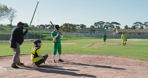 Batter Preparing to Hit While Catcher Squatting and Umpire Observing on Baseball Diamond