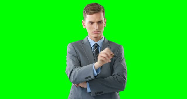 Businessman wearing a suit writing on an invisible board with green screen background. Ideal for projects involving technology, business presentations, virtual meetings, corporate training, or advertisements for business services.