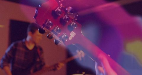 Framing Red Guitar Headstock While Bassist Performs Under Colorful Stage Lights