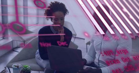 Colleagues collaborating over laptop with magenta data overlay in modern lounge