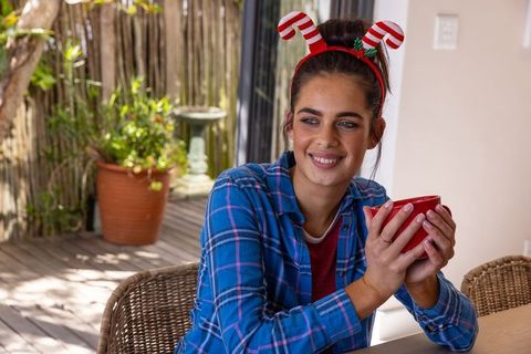 Smiling woman enjoying hot drink at holiday deck gathering