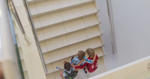 Boys running upstairs in school captured from above