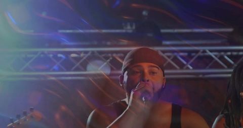 Energetic performer singing live on stage with colorful lighting effects