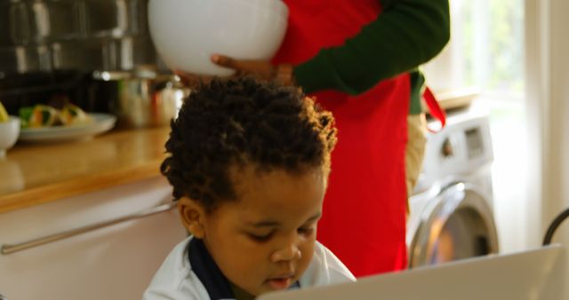 Young Boy Learning on Laptop While Parent Cooking in Kitchen - Download Free Stock Images Pikwizard.com