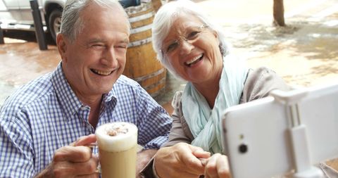 Senior Couple Enjoying Coffee and Taking Selfie at Outdoor Cafe