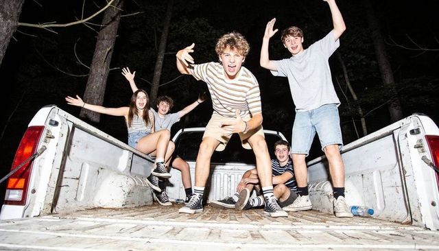 Energetic teens posing in pickup truck bed at night celebrating friendship and adventure