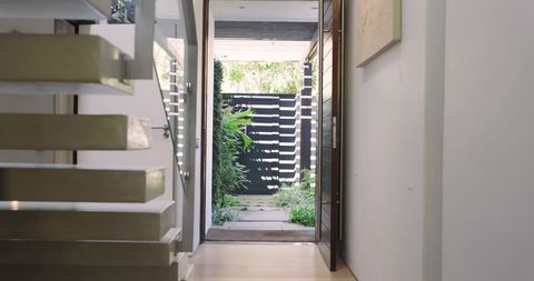Modern home entryway with floating stairs and courtyard view