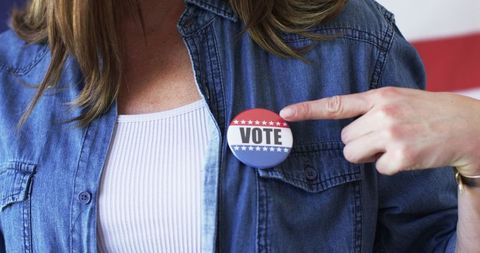 Woman pointing at vote badge on denim jacket