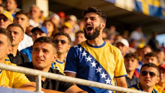 Shouting bosnia and herzegovina supporter wearing flag jersey cheering in stadium crowd