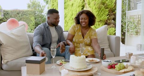 Joyful Couple Celebrating on Cozy Patio with Cake and Champagne