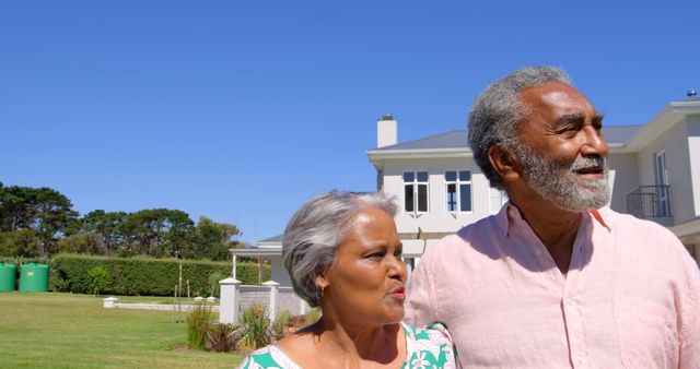 Front view of senior black couple walking together in garden on a sunny day. They are smiling and looking away 4k