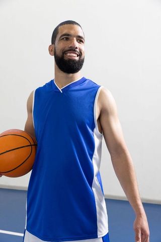 Smiling Basketball Player Holding Ball on Indoor Court