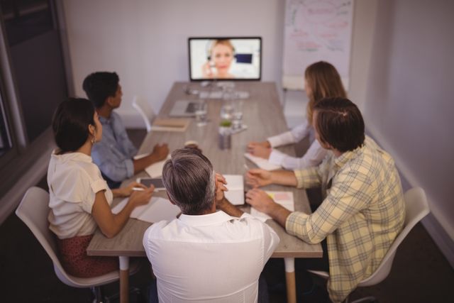 Business team attending a video conference meeting in an office. Ideal for illustrating remote work, corporate communication, teamwork, and modern business practices. Useful for articles, presentations, and marketing materials related to business collaboration and technology.