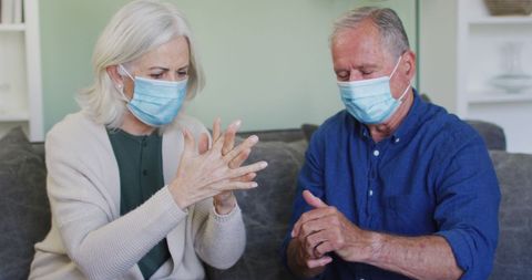 Senior Couple Wearing Masks Sanitizing Hands Indoor