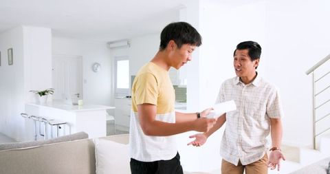 Excited Young Man Discussing Letter with Friend in Modern Living Room