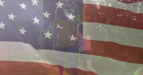 Patriotic mother and daughter walking sunlit garden path