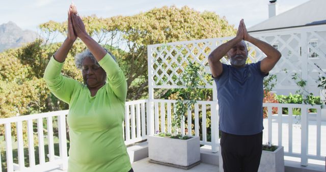 Relaxed african american senior couple practicing yoga on patio. active and healthy retirement lifestyle at home and garden.