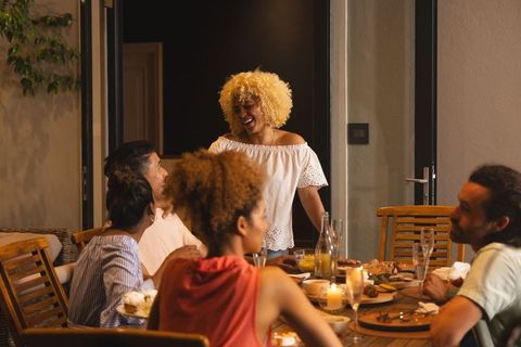 Cozy candlelit outdoor dinner gathering with diverse friends laughing and hosting