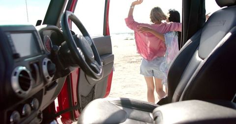 Friends Embracing Next to SUV on Beach Adventure