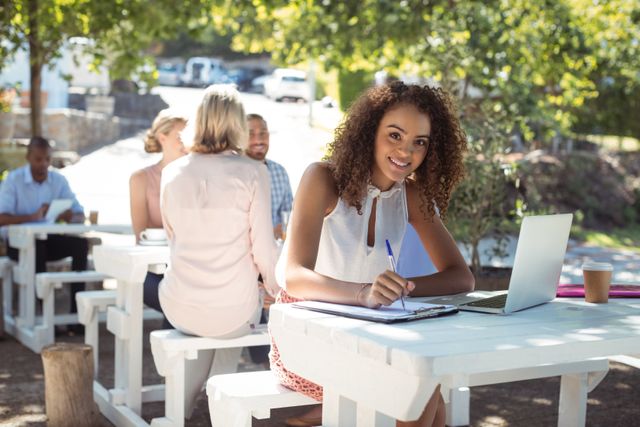 Portrait of smiling beautiful woman writing on clipboard in restaurant