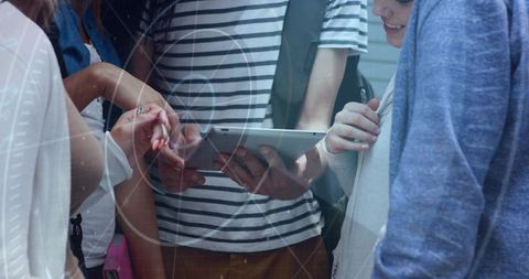 High school students crowding around tablet in hallway collaborating on digital learning