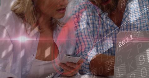 Colleagues collaborating with smartphone and laptop, holding phone and viewing digital data overlay