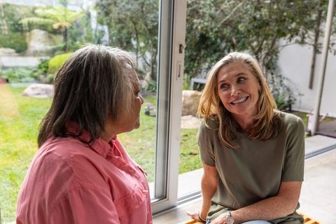 Smiling Women Friends Enjoy Relaxed Conversation by Patio Window